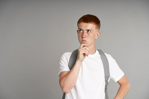 Young ginger male student thinking about something