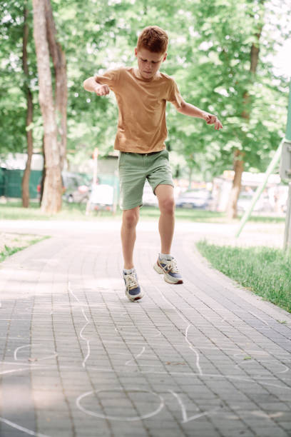 istock Ginger boy playing at hopscotch in summer day 1413614508