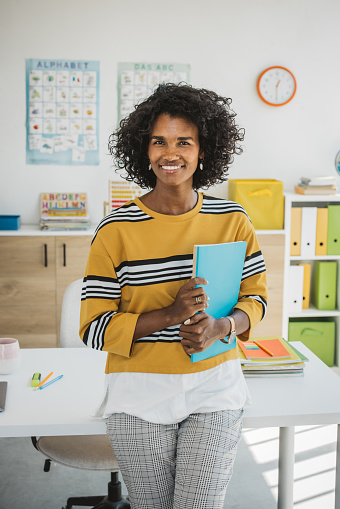 Teacher at classroom sitting on desk, preparing for next school year. Waiting for students.