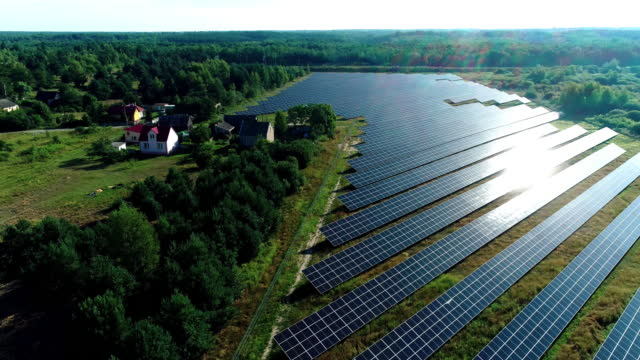 Aerial view of Solar Panels Farm (solar cell) in the sunlight. Surrounded by trees and residential area