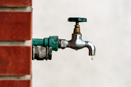 Back yard outdoor garden faucet with drop of water, selective focus