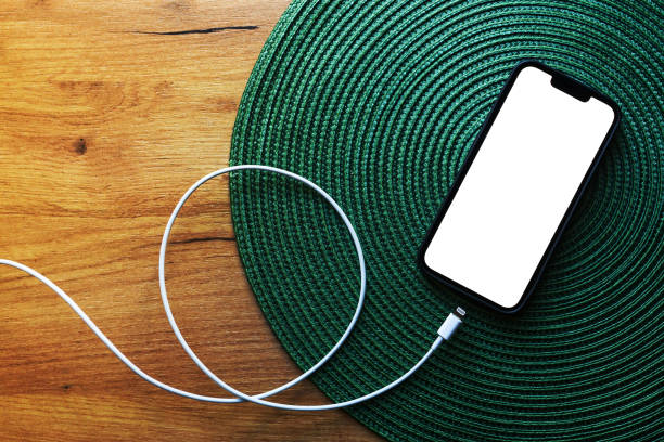 smartphone con pantalla de maqueta en blanco y cable de cargador de móvil sobre la mesa, vista superior - overhead wires fotografías e imágenes de stock