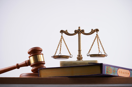 Closeup of mallet and legal book with justice scale on table in courtroom