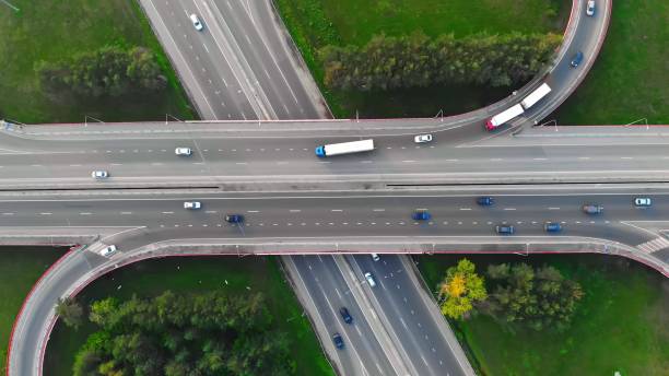 ドローンは、次々に移動する多数の車と異なる方向に多くのインターチェンジで、トラックから目的の出口に車線を変更する交通中にトラック上を飛行します - land vehicle multiple lane highway driving traffic ストックフォトと画像
