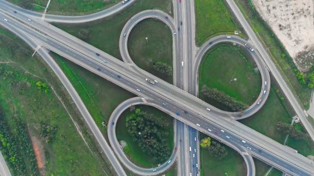 istock Top view of the highway with many interchanges in different directions with a large number of cars that move one after another and change lanes to the desired exit from the highway. 1413625897