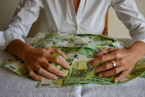 mature woman embracing pile of 100 Euro bank notes