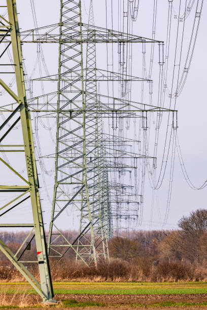 Many steel pylons with power lines spoil rural nature in Germany stock photo
