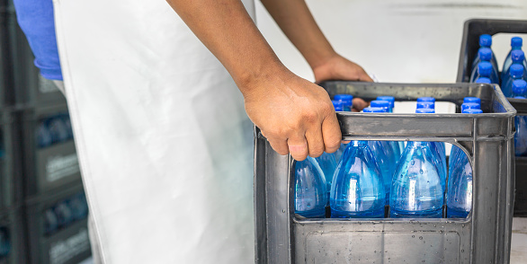 Close-up of a blue water bottle being packaged as a drinking water product in a factory where a worker produces drinking water in a clean drinking water plant  clean drinking water production business
