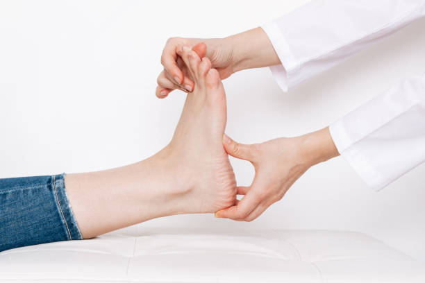 examination of a young woman by an female orthopedist. cropped shot of doctor holding a painful foot - plattfot bildbanksfoton och bilder