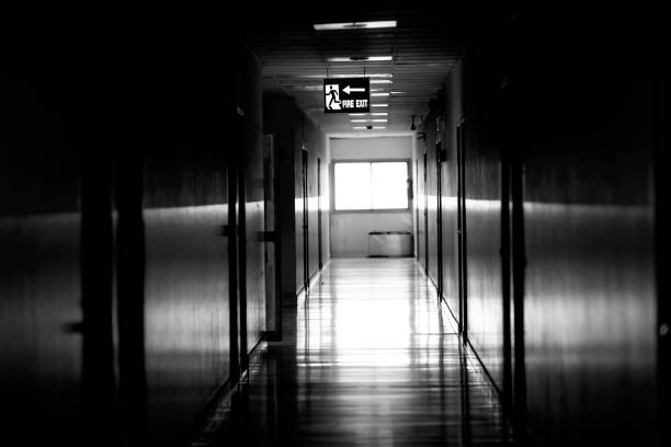 istock Dramatic black and white of fire exit sign on the corridor of the building 1413632426