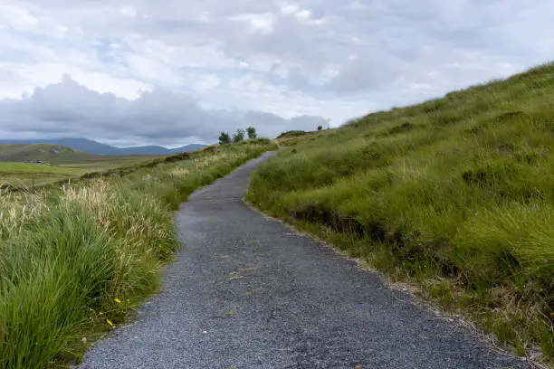 landscape view of hiking trail leading through the meadows and hills of the Ballycroy National Park in County Mayo