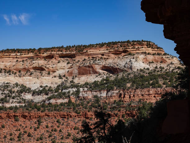 istock Red sandstone tower with banded desert cliffs in the distance. 1413635415