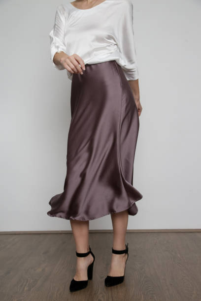 Series of studio photos of young female model wearing white silk satin batwing short sleeve blouse with mocha color midi skirt stock photo