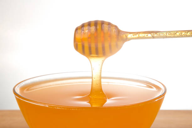 istock fresh floral honey dripping from a spoon into a transparent plate on a white background. organic vitamin health food 1413636423