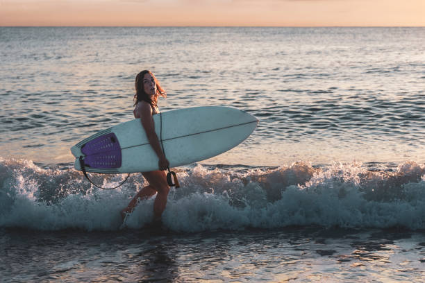 istock Woman on beach with surfboard under her arm with cold expression 1413636736
