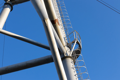 Service ladder on power line support against blue sky background