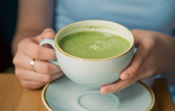 istock Close-up, a cup with green matcha drink in female hands. 1413636957