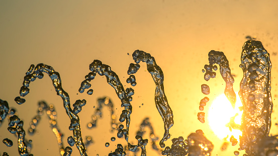 silhouettes of drops falling water fountain against the backdrop of the setting sun