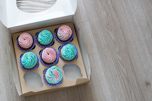 a box of cupcakes with two empty space lies on the table