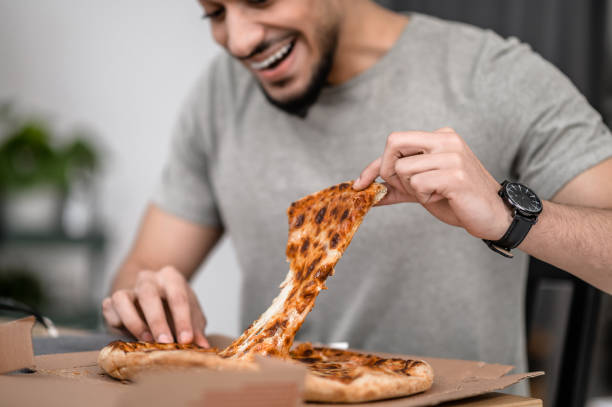 istock Man tearing pizza into portions sitting at table 1413639661