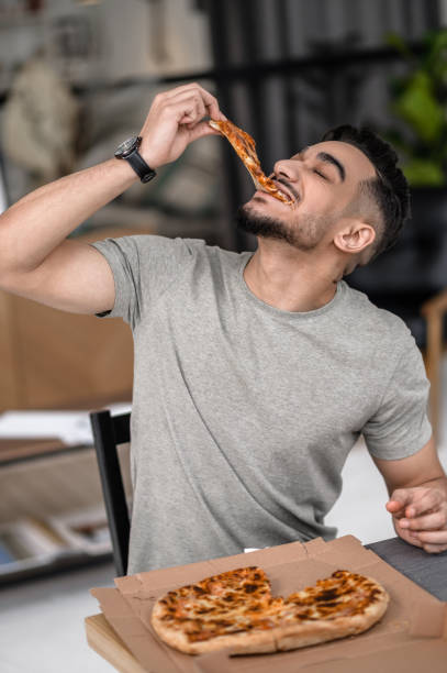 uomo con gli occhi chiusi che morde la pizza - bon appetite foto e immagini stock