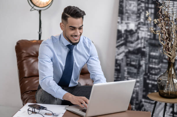 istock Business man typing on laptop sitting indoors 1413639710