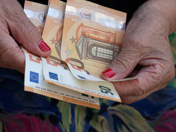 Photo of Woman's hands are holding a few euro coins. Pension, poverty, social problems and the theme of old age. Saving.