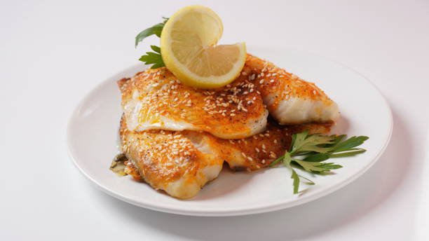 istock Fresh backed tilapia fillet on white plate with lemon and herbs 1413640895