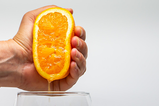 Macro photo of an orange squeezed with a hand.  Orange juice.  Side photo.  Citrus fruit juice.  Natural juices.