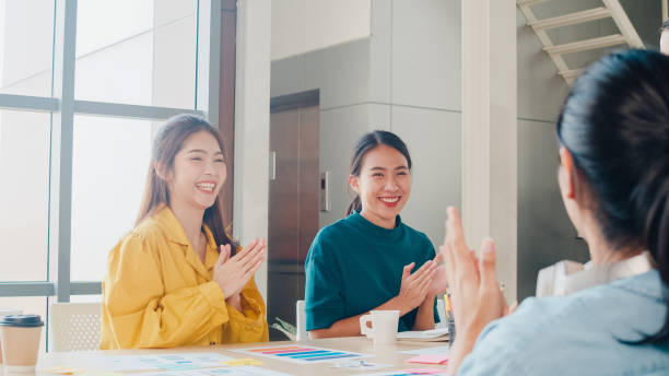 Group of Asia young creative people in smart casual wear discussing business celebrate giving five after dealing feeling happy and signing contract or agreement in office. stock photo