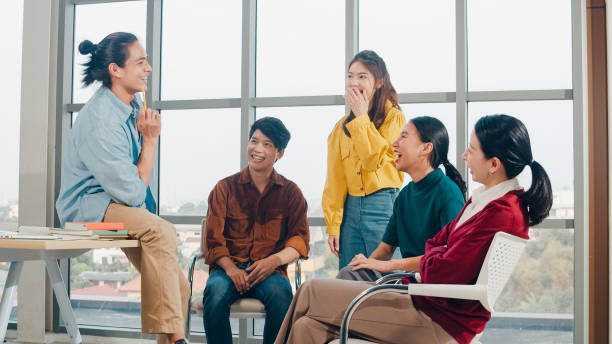 Group of young college students in smart casual wear on campus. Friends brainstorming meeting talking and discussing work ideas new design project in modern office. stock photo