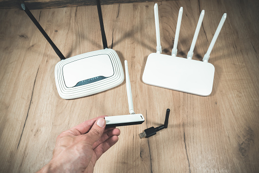 Man choose of different types of Wi-Fi routers, modern and old technology. Wireless ethernet connection signal. USB Wifi Receiver Wireless Network Card. High Speed Antenna Wifi Adapters.