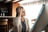 Mature woman with headache while using the computer at home