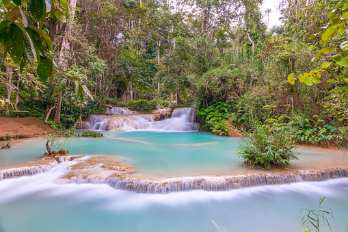 Magical turquoise blue colours of Kuang Si waterfalls Luang Prabang Laos. these waterfalls in the Mountains of Luang Prabang Laos flow all year round in the natural national park rainforest