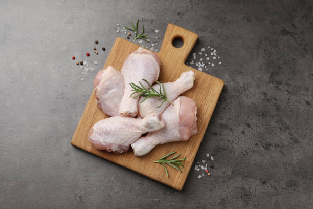 istock Raw chicken drumsticks with rosemary and spices on grey table, flat lay 1413648021