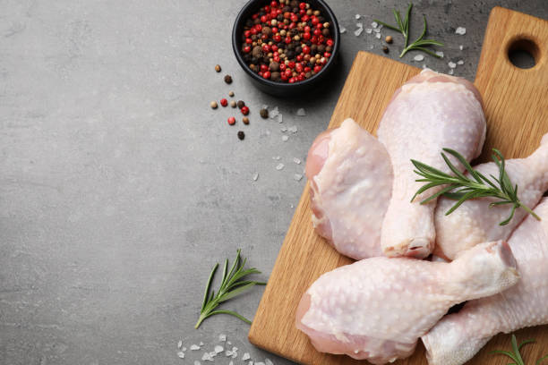 istock Raw chicken drumsticks with rosemary and spices on grey table, flat lay. Space for text 1413648192