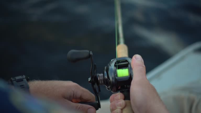 The fisherman spins the spinning on the river. A man is engaged in sport fishing during the day. Spinning close up.