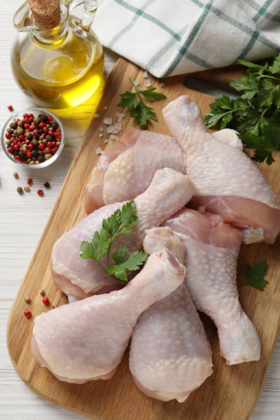 istock Raw chicken drumsticks and ingredients on white wooden table, flat lay 1413648355