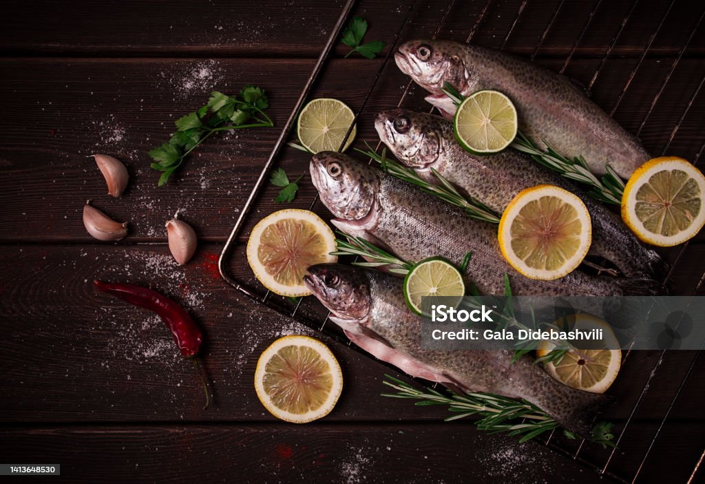 Raw rainbow trout, with lemon and herbs, on a wooden table, no people, Rainbow Trout Stock Photo