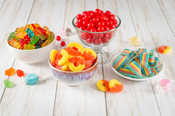 Assortment of candy in bowls on a light wood background