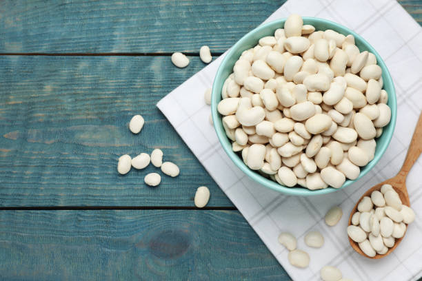istock Uncooked white beans on blue wooden table, flat lay. Space for text 1413649623