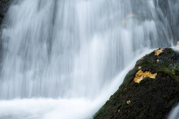 istock Mossy wet rock in front of a blurred waterfall 1413649819