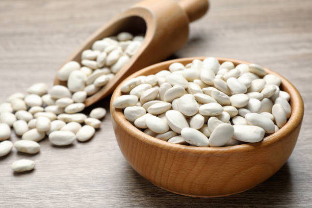 istock Raw white beans, bowl and scoop on wooden table, closeup 1413649828