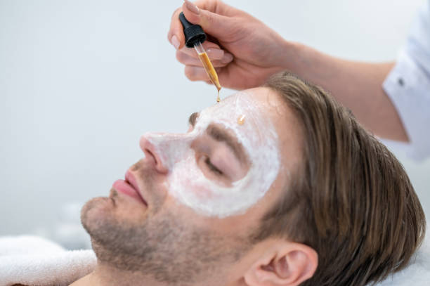 istock Professional cosmetologist applying hydrating mask on mans eye area 1413651142