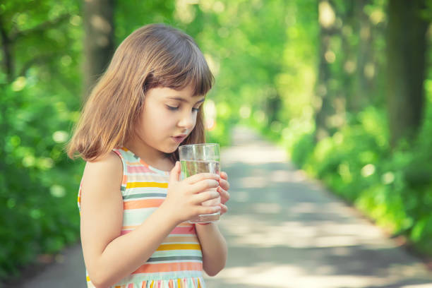 istock Cute Girl Drinking Water While Standing Outdoors 1413651461