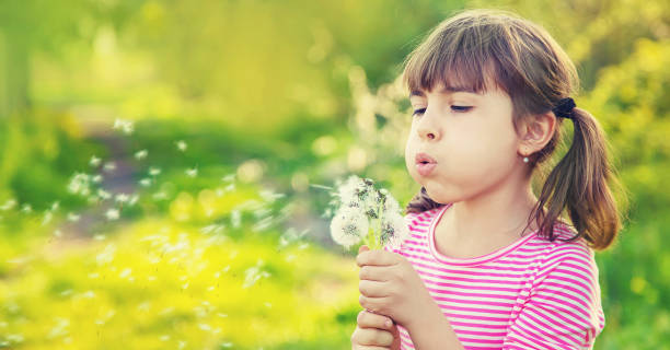 istock Cute Girl Blowing Flower 1413651648