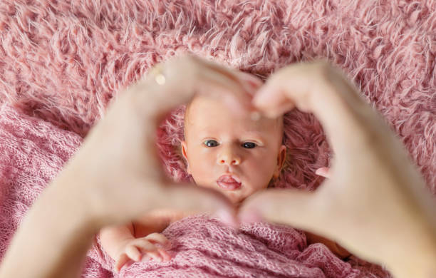 istock Woman Gesturing Heart Shape Over Baby On Bed 1413651663