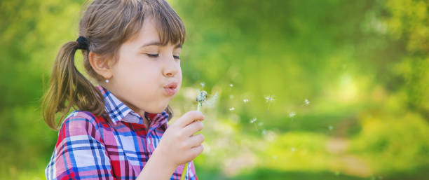istock Cute Girl Blowing Flower 1413651834