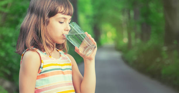 istock Cute Girl Drinking Water While Standing Outdoors 1413652008