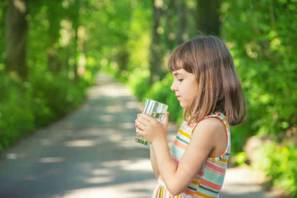 istock Cute Girl Drinking Water While Standing Outdoors 1413652026